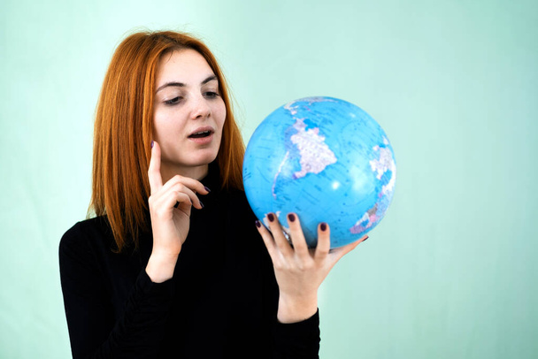 Portrait of a happy young woman holding geographic globe of the world in her hands. Travel destination and planet protection concept. - Foto, Bild