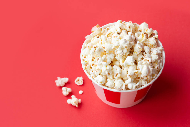 popcorn in a paper striped box on a red background with copy space. American food background. Red background. Fast food. - 写真・画像