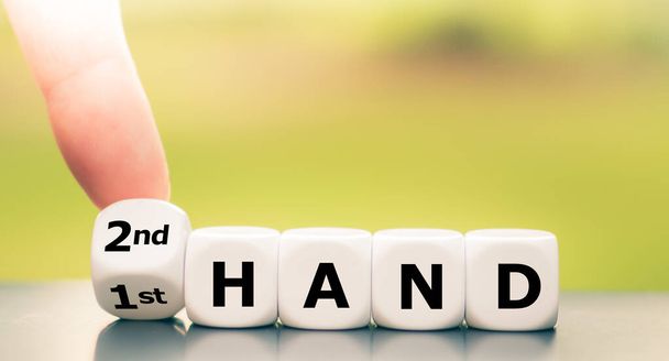 Hand draait dobbelstenen en verandert de uitdrukking "1e hand" in "2e hand". - Foto, afbeelding