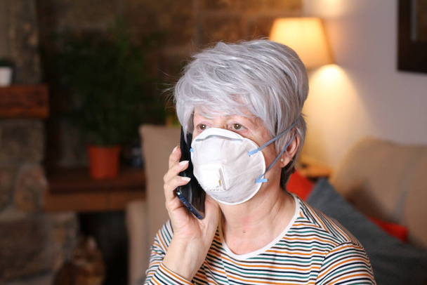 κοντινό πορτρέτο της όμορφης ώριμης γυναίκας με προστατευτική ιατρική μάσκα στο σπίτι - Φωτογραφία, εικόνα