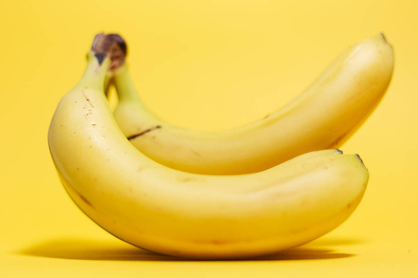 Close-up of bananas on background of yellow color. - 写真・画像