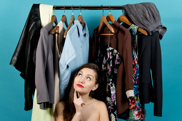 Young girl and a hanger with different clothes - Photo, Image
