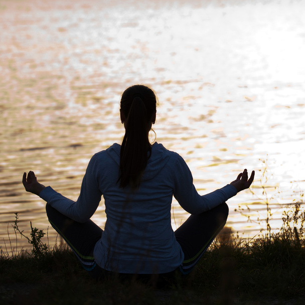 Silhouette einer Frau in meditativer Pose - Foto, Bild