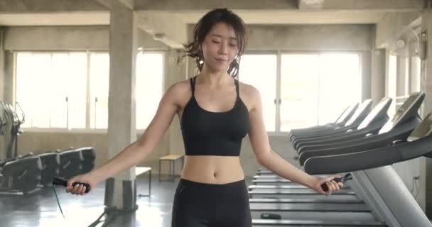 Atraktivní asijská žena skákání s skákacím lanem ve fitness wellness studio tělocvičně. Zpomal. Zdravotní péče, cvičení a sport koncept. - Záběry, video