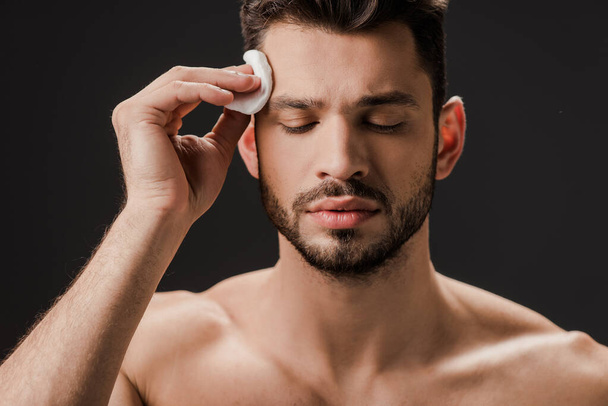 Brünette sexy nackter Mann mit kosmetischen Baumwollkissen isoliert auf grau - Foto, Bild