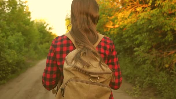 Szabad lány utazó sétál az erdőben egy hátizsákkal. Egy túrázó nő sétál az erdőben. Boldog túrázós lány a nyári parkban. Tinédzser lány kalandok nyaralni. közelkép. - Felvétel, videó