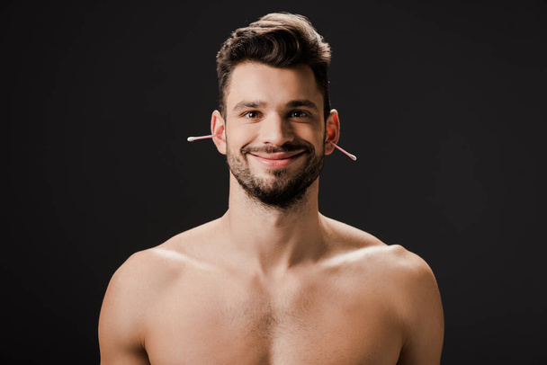 улыбающийся голый мужчина с тампонами на ушах, изолированными на черном
 - Фото, изображение