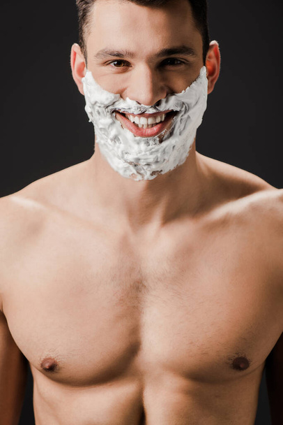 cheerful naked man with shaving foam on face isolated on black - Fotoğraf, Görsel