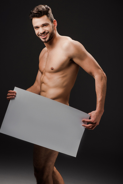 セクシーな裸の男を笑顔黒に隔離された空白のプラカードを保持 - 写真・画像