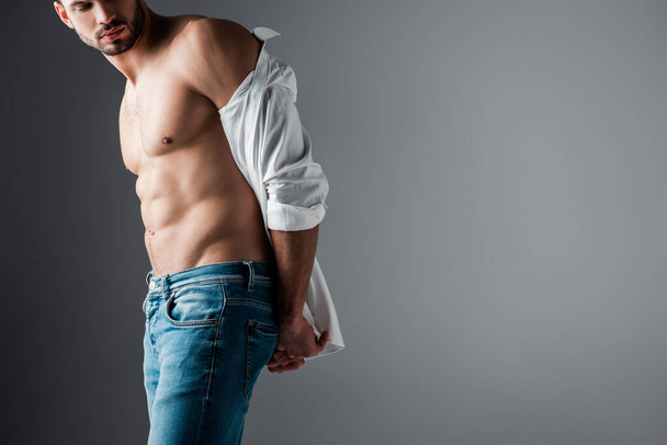 sexy muscular man in white shirt and jeans on grey - 写真・画像