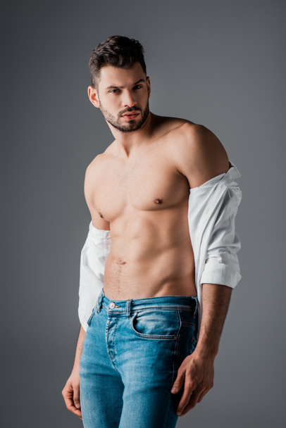 brunette sexy man in white shirt and jeans isolated on grey - Foto, Imagem