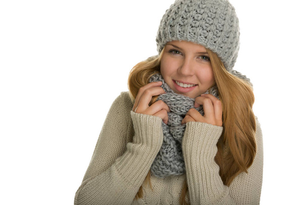 Portrait of a young woman / girl. She keeps warm in her knitted sweater,scarf and beanie dresses - Foto, Imagen