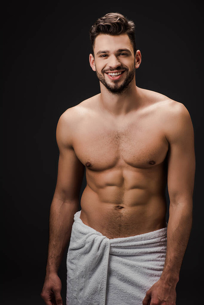 smiling sexy muscular man in towel isolated on black - Photo, Image