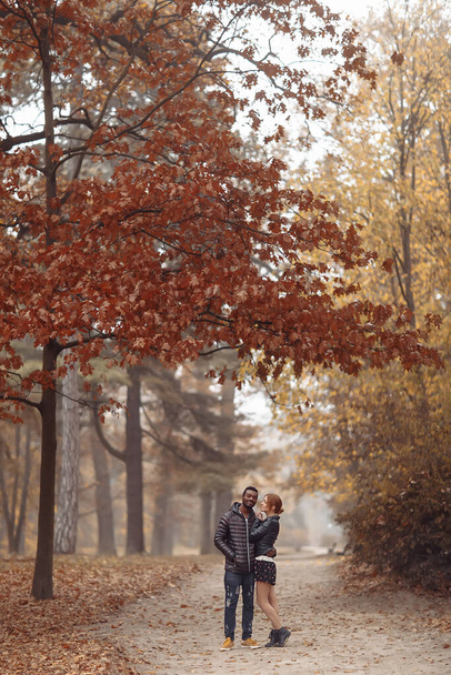 Happy interracial couple posing in autumn park, black man and white redhead woman - Foto, imagen