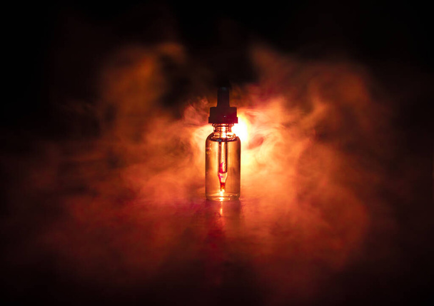 Vape-Konzept. Rauchwolken und Dampfflaschen auf dunklem Hintergrund. Lichteffekte. Nützlich als Hintergrund oder Vapewerbung oder Vapehintergrund. Selektiver Fokus - Foto, Bild