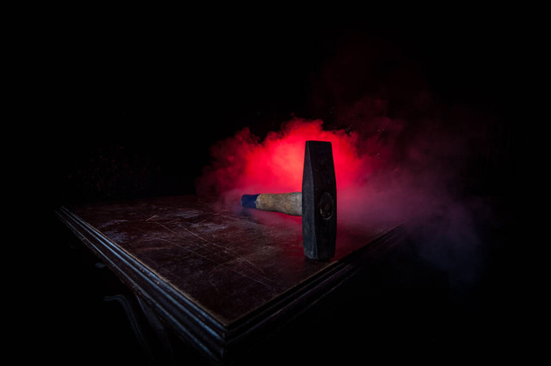 Oude vintage hamer op een houten tafel voor een donker getinte mistige achtergrond. Selectieve focus. - Foto, afbeelding