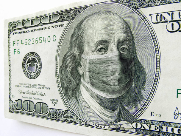 This photo illustration of Ben Franklin wearing a healthcare surgical mask on a one hundred dollar bill illustrates the Coronavirus, the protection of wearing a mask during international travel, and economic costs affecting business, transportation,  - Photo, Image