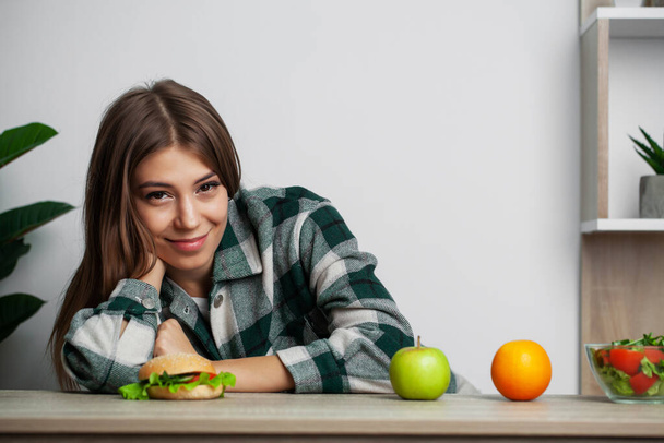 Menina faz uma escolha entre alimentos saudáveis e prejudiciais
 - Foto, Imagem
