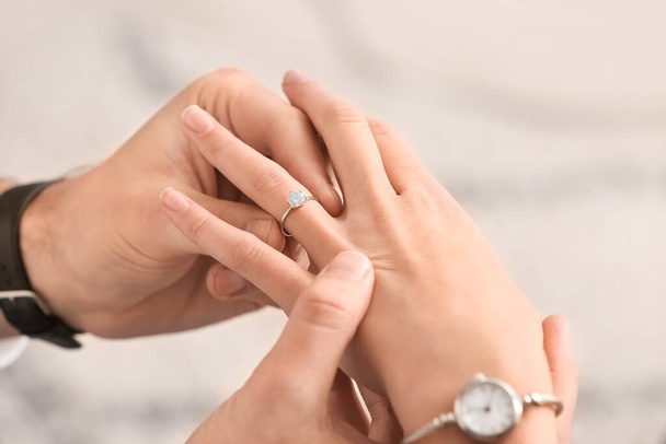 Young man putting ring on finger of his fiancee after marriage proposal, closeup - Valokuva, kuva
