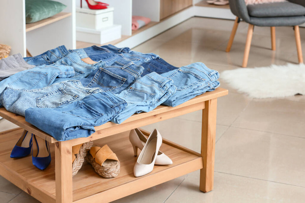 Table with stylish jeans clothes and female shoes in modern store - Foto, imagen