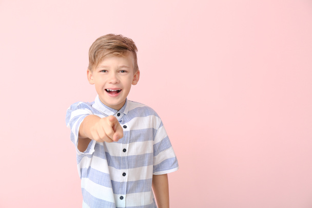 Happy little boy pointing at viewer on color background - Фото, изображение