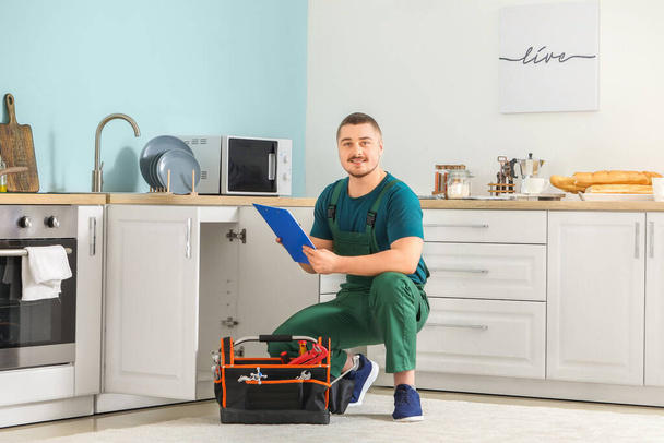 Portrait of handsome plumber in kitchen - Photo, Image