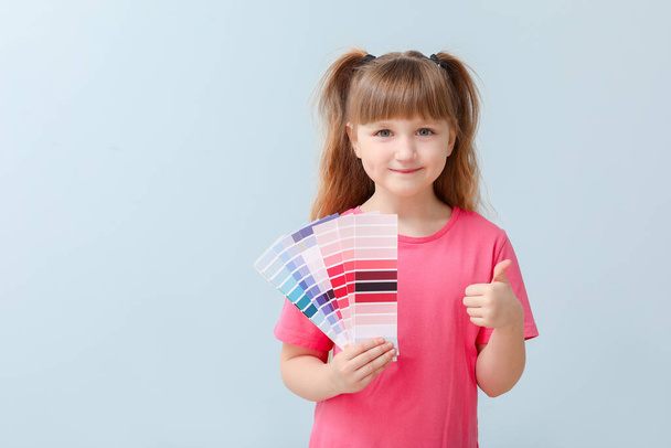 Kleines Mädchen mit Farbpaletten auf blauem Hintergrund - Foto, Bild