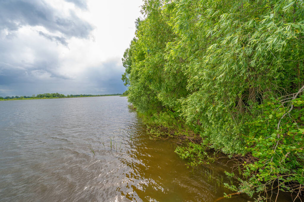 літнє фото, потужні грозові хмари, блакитне небо, темна різка вода, туристи йдуть уздовж річки Кама. - Фото, зображення