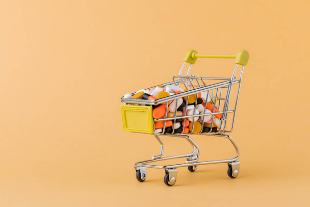 Prášky a nákupní košík na žlutém pozadí Koncept nákupu léků, ceny za léčbu. Prodej v lékárně - Fotografie, Obrázek