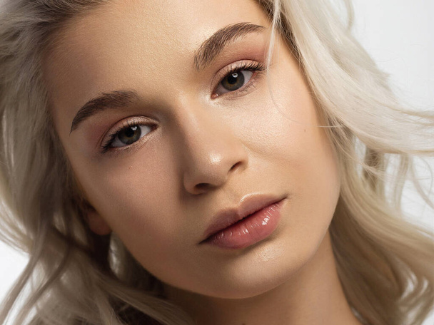 Closeup of beauty woman with clean shiny skin and natural cosmetics. Beautiful extrem eyelash and full lips of a well-groomed girl demonstrate spa procedures, injections in beauty parlor. Blonde hair - Valokuva, kuva