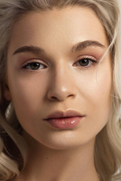 Closeup portrait of a woman with developing straight hair. Sweet tender young girl blonde. Natural lipstick, transparent clean skin. Skin care natural cosmetics in the spa salon or cosmetology. - Valokuva, kuva