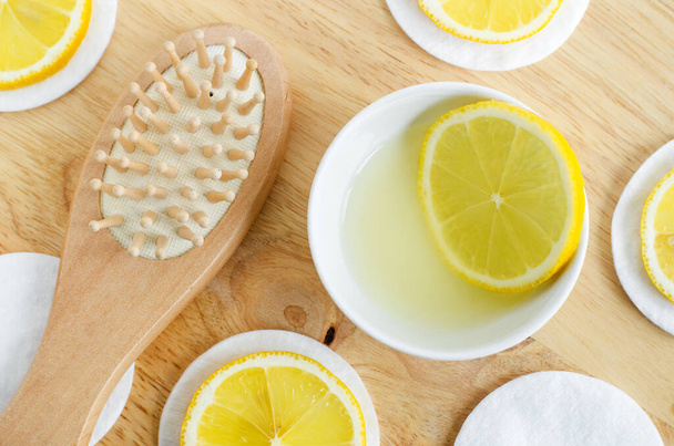 Lemon juice, lemon slices and wooden hairbrush. Ingredients for preparing homemade hair mask or face toner. Natural beauty treatment recipe and zero waste concept. Top view, copy space.  - Photo, Image