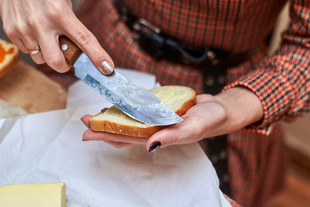 Woman smears butter on bread. Making a sandwich. - Valokuva, kuva