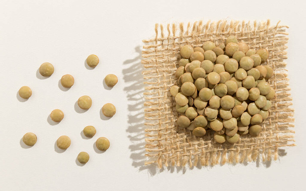 Lens culinaris is scientific name of Lentil legume. Also known as Lentilha Canadense (portuguese) or Lentejas (spanish). Close up of grains spreaded over white table. - Valokuva, kuva