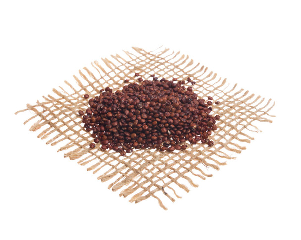 Chenopodium quinoa είναι επιστημονική ονομασία του σπόρου Red Quinoa. Σπόροι πάνω από το ύφασμα Hessian, απομονωμένο λευκό φόντο. - Φωτογραφία, εικόνα