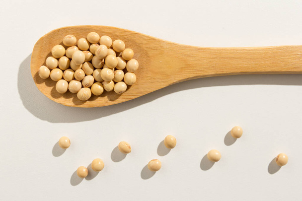 Glycine max is de wetenschappelijke naam van sojabonen peulvruchten. Ook bekend als Soja Bean en Soja. Gezonde granen op een houten lepel. Witte achtergrond. - Foto, afbeelding