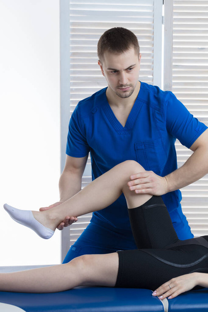 The orthopedic doctor makes a diagnosis of the muscle tone on the girl's legs. Manual therapy - Fotó, kép