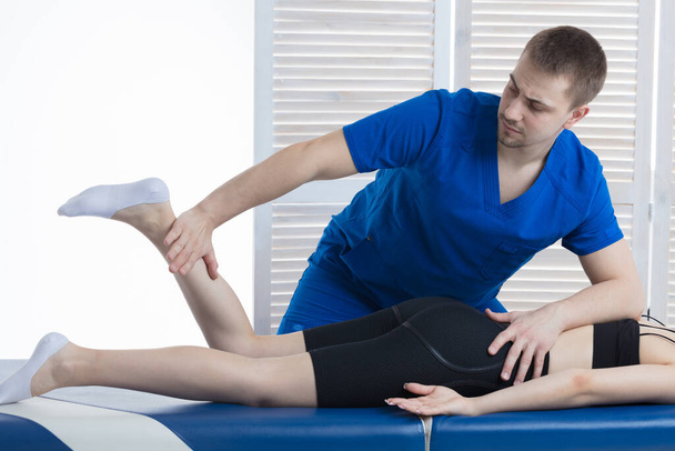 The orthopedic doctor makes a diagnosis of the muscle tone on the girl's legs. Manual therapy - Foto, Bild