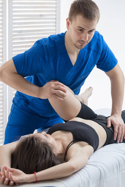 The orthopedic doctor makes a diagnosis of the hip joints for the girl. A chiropractor works - Foto, afbeelding