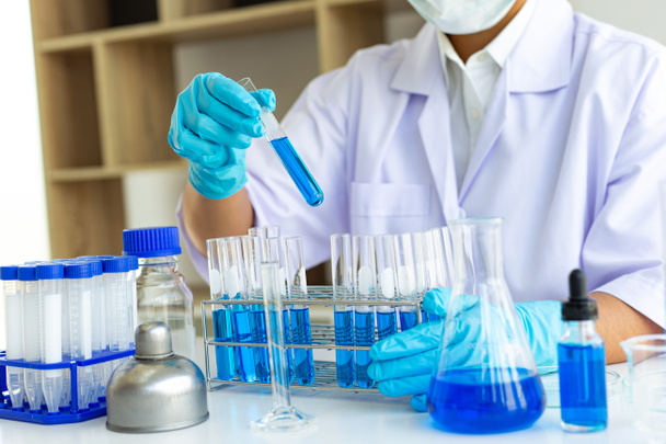 Tiedemiehet kuljettavat sinisiä kemiallisia koeputkia valmistellakseen kemiallisen koostumuksen ja biologisen massan määrittämistä tieteellisessä laboratoriossa, tiedemiehet ja laboratoriokonseptin tutkimus. - Valokuva, kuva