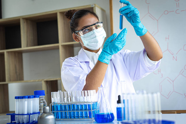 Gli scienziati stanno trasportando provette chimiche blu per prepararsi alla determinazione della composizione chimica e della massa biologica in un laboratorio scientifico, Scienziati e ricerca in laboratorio Concetto. - Foto, immagini