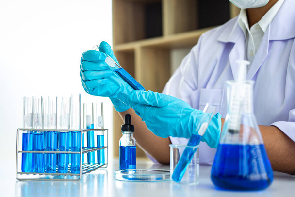 Οι επιστήμονες μεταφέρουν μπλε χημικές δοκιμαστικές λυχνίες για να προετοιμαστούν για τον προσδιορισμό της χημικής σύνθεσης και της βιολογικής μάζας σε ένα επιστημονικό εργαστήριο, Επιστήμονες και έρευνα στο εργαστήριο Concept. - Φωτογραφία, εικόνα