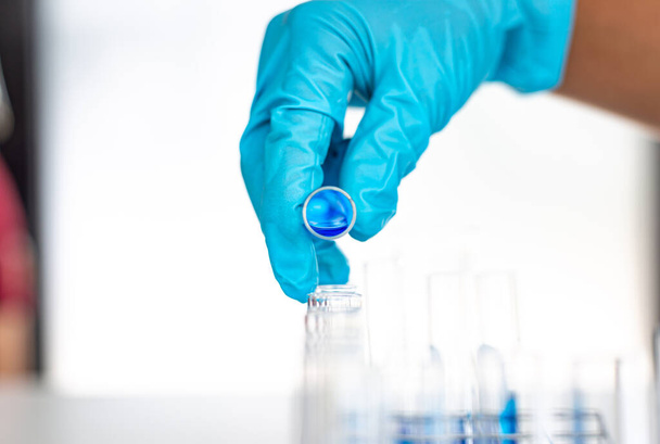 科学者たちは、研究室での化学組成と生物学的質量の決定のために準備するために青色の化学試験管を持っています,研究室での科学者や研究コンセプト. - 写真・画像