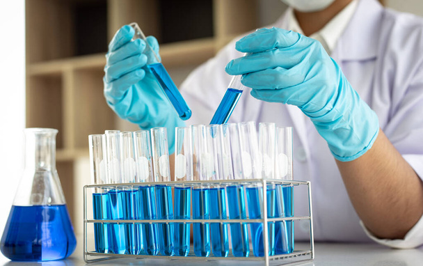 Naukowcy niosą niebieskie chemiczne probówki, aby przygotować się do określenia składu chemicznego i masy biologicznej w laboratorium naukowym, Naukowcy i badania w laboratorium Concept. - Zdjęcie, obraz