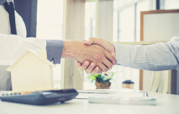 Оба бизнесмена пожимают руку, чтобы поздравить их с успешным подписанием договора с агентом по страхованию жилья, покупке жилья и страхованию Концепции
. - Фото, изображение