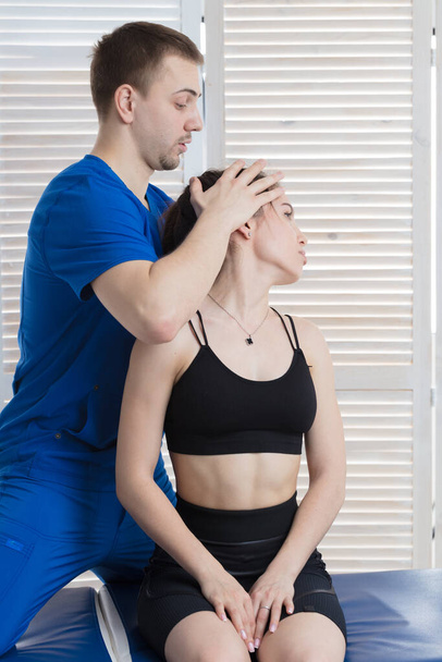 The doctor makes a diagnosis of the head and cervical spine of a young girl. Massage and manual therapy - Photo, image