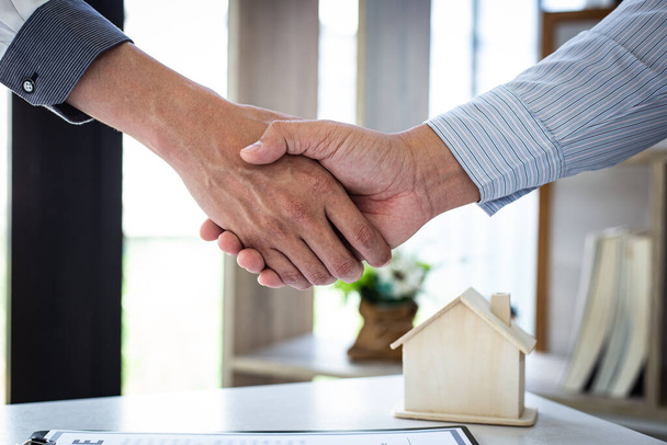 Оба бизнесмена пожимают руку, чтобы поздравить их с успешным подписанием договора с агентом по страхованию жилья, покупке жилья и страхованию Концепции
. - Фото, изображение