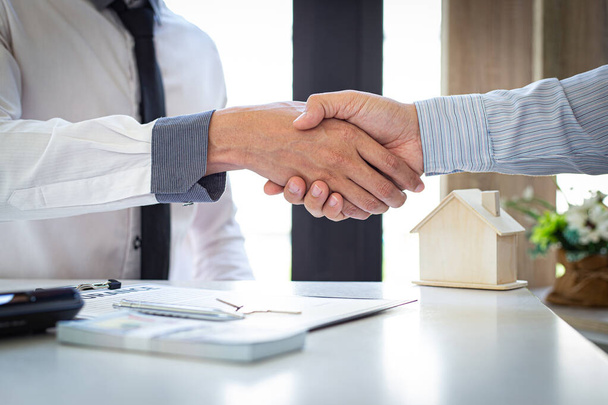 Beide ondernemers schudden elkaar de hand om hen te feliciteren met hun succesvolle ondertekening van een contract met een woningverzekeraar, woningaankoop en verzekering Concept. - Foto, afbeelding