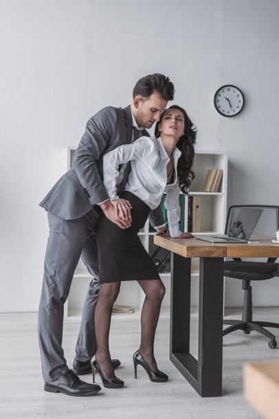 handsome businessman touching seductive secretary in office - Photo, Image