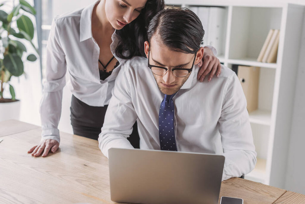 чувственная деловая женщина трогает плечо работающего коллеги, соблазняя его в офисе
 - Фото, изображение